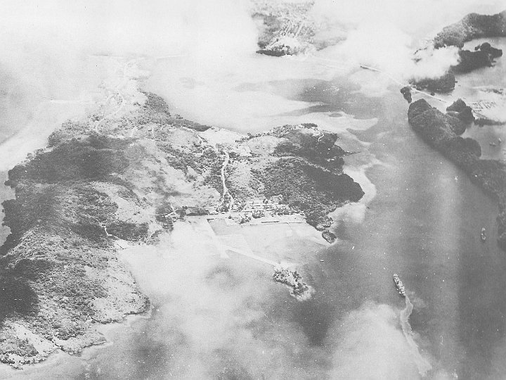 attack on palau-14.JPG - Bomb and rocket hits on the Goshu Maru (lower right) have produced some smoke and an oil slick. The Ryuko Maru is anchored just off the northern shore of Ngargol (right)